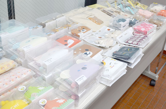 説明会会場の様子と参加者にお渡ししている卒業生がデザインした「POCHI」「ころまるさん」シリーズのグッズ